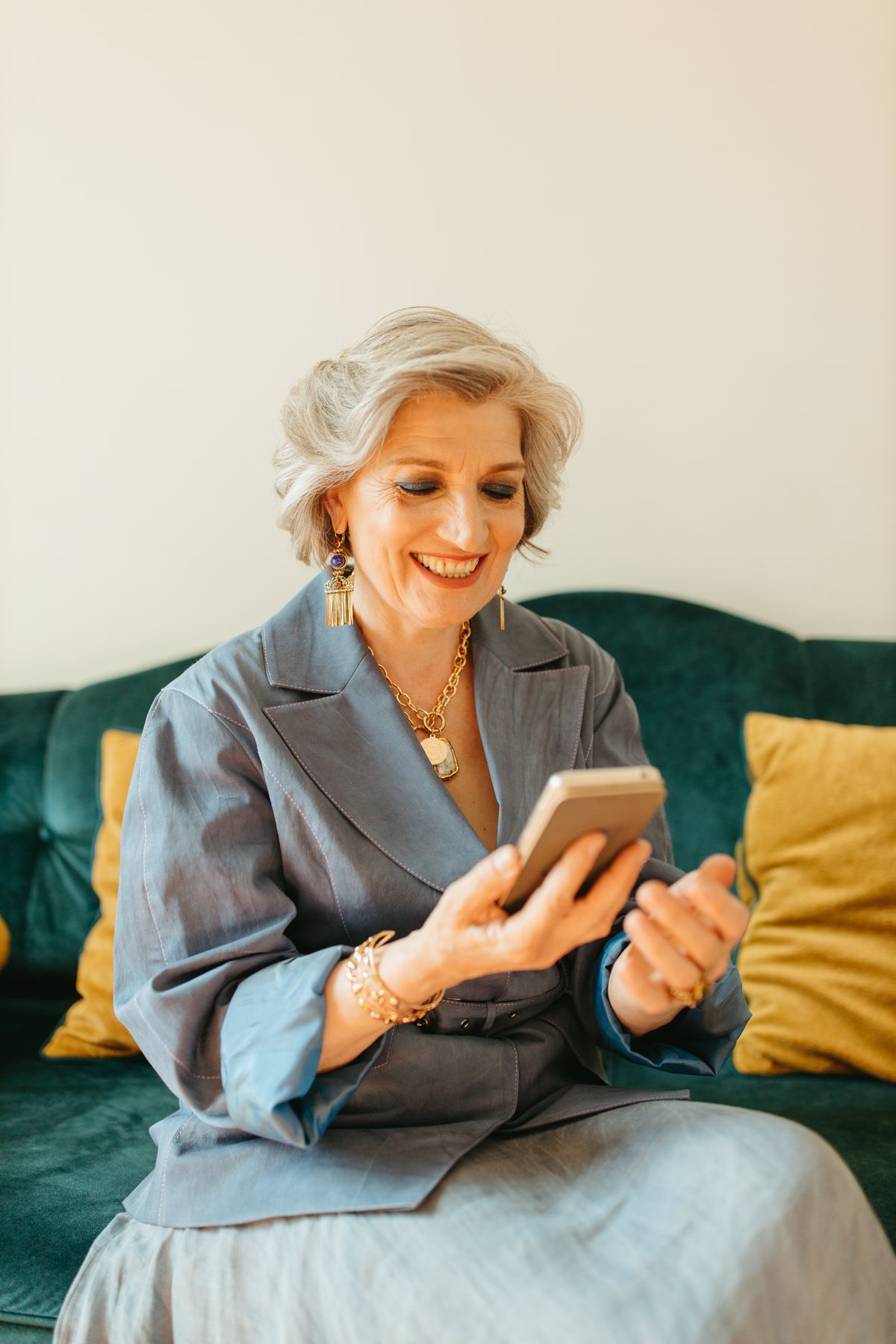 A smiling senior woman happily texting on her smartphone at home